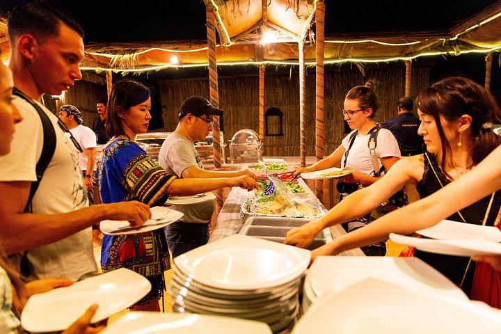 Les voyageurs se servent de la nourriture dans un camp du désert lors d'un safari près de Dubaï.