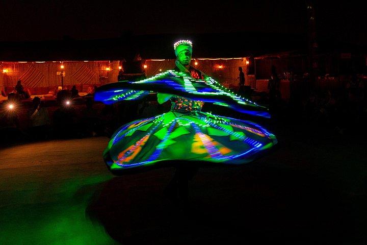 Une danseuse colorée de Tanoura tourne autour d'un spectacle dans un camp du désert près de Dubaï.