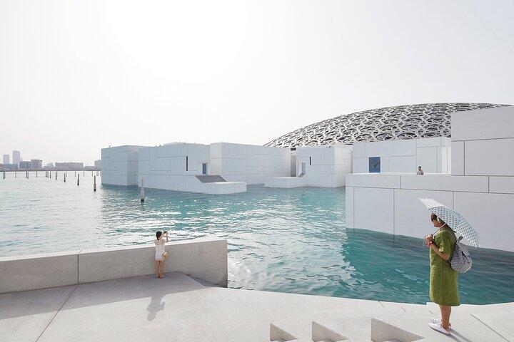 S'émerveiller devant l'éclat architectural : un touriste admire de loin le Louvre Abu Dhabi